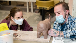 Ceramics instructor and student pay attention to details on a project in the clay studio.