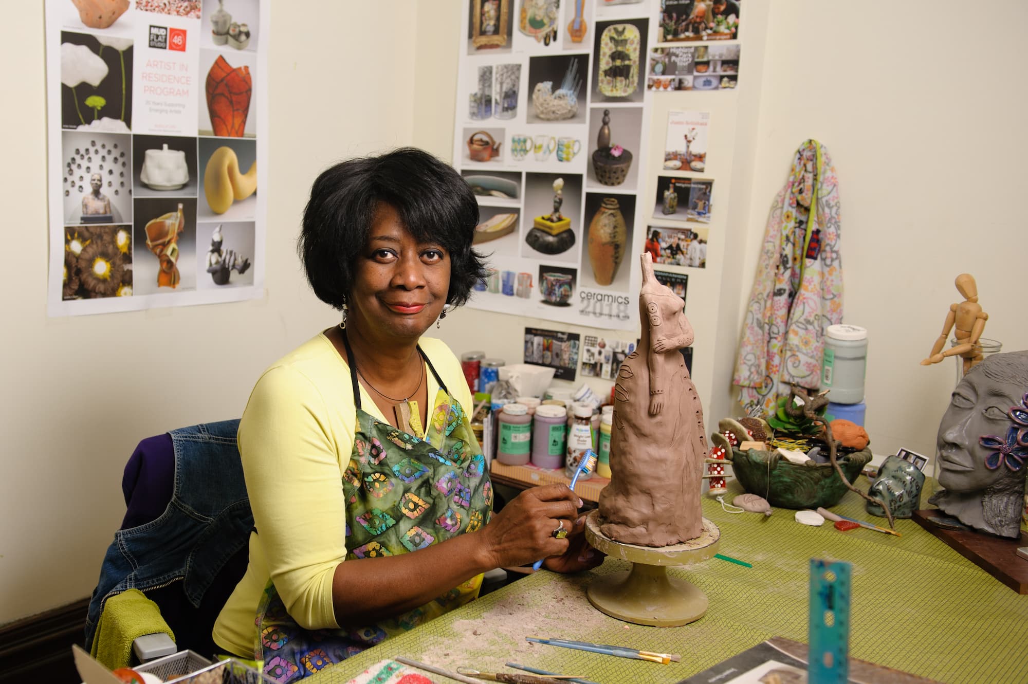 Collaborative studio member Janet Watkins looks at the camera while working on a ceramic sculpture.